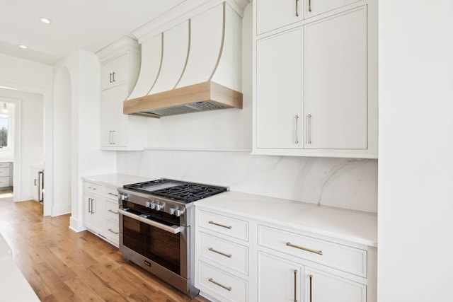 kitchen featuring range with two ovens, light countertops, white cabinetry, light wood-type flooring, and custom exhaust hood