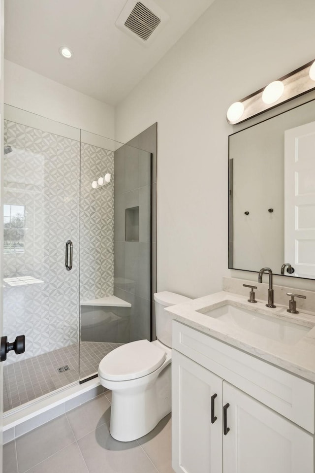 bathroom with tile patterned floors, toilet, vanity, a shower stall, and visible vents