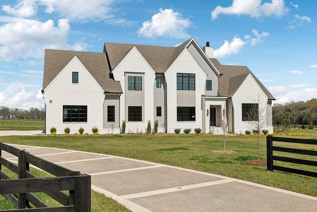 view of front of property with roof with shingles, a front yard, fence, and a chimney