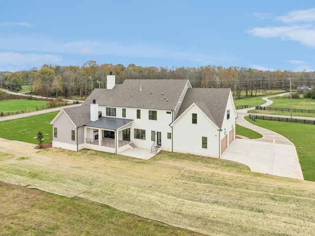 back of house featuring concrete driveway, a chimney, fence, a lawn, and a garage