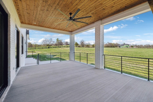 wooden deck featuring a ceiling fan, a rural view, and a yard
