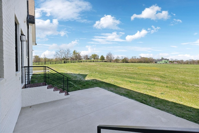 view of yard with fence, a patio, and a rural view