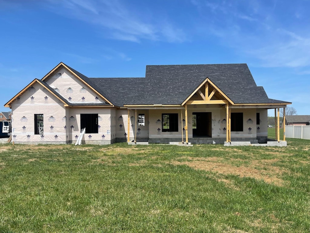 view of front of home with a front lawn, roof with shingles, and a patio area