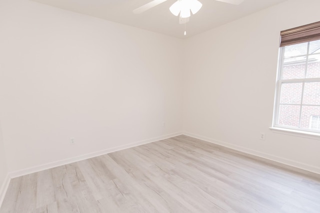 empty room featuring a wealth of natural light, light wood-type flooring, ceiling fan, and baseboards
