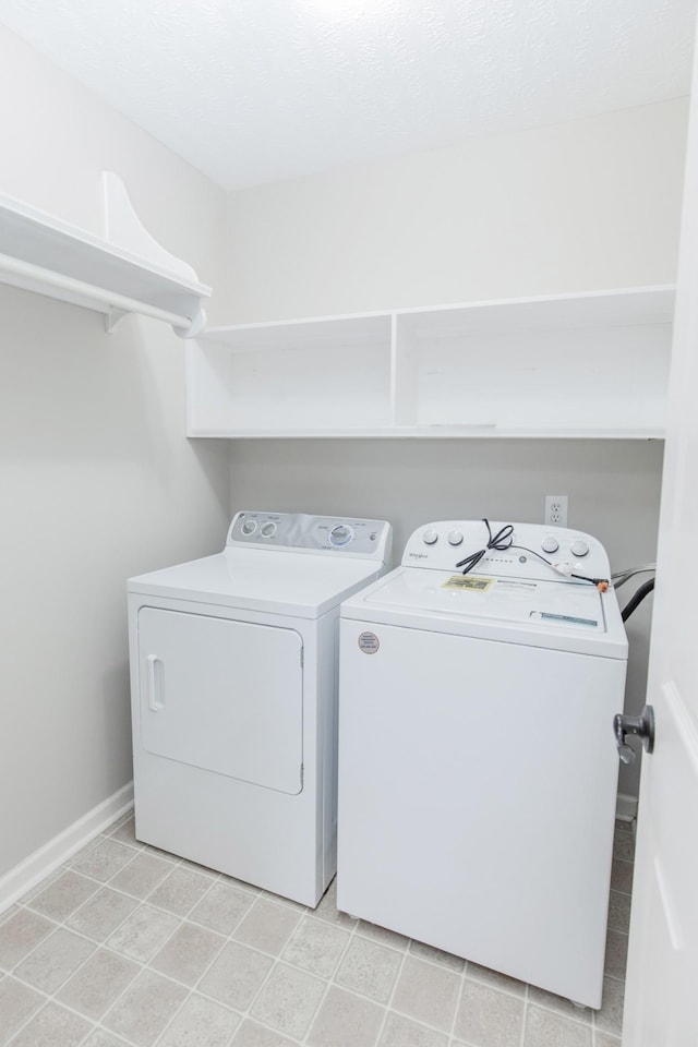 clothes washing area with independent washer and dryer, baseboards, and laundry area
