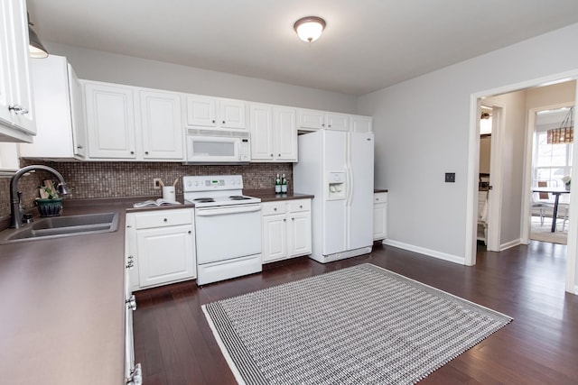 kitchen with decorative backsplash, white cabinets, white appliances, dark wood finished floors, and a sink
