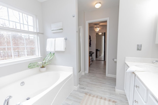 full bath with vanity, a bath, baseboards, ceiling fan, and wood finished floors