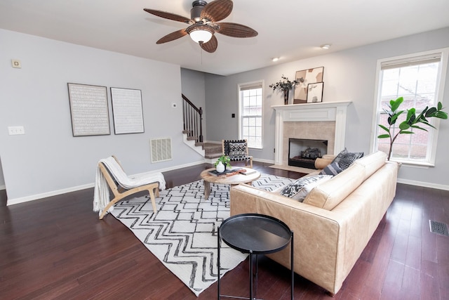 living area with stairway, baseboards, dark wood-style floors, visible vents, and a ceiling fan