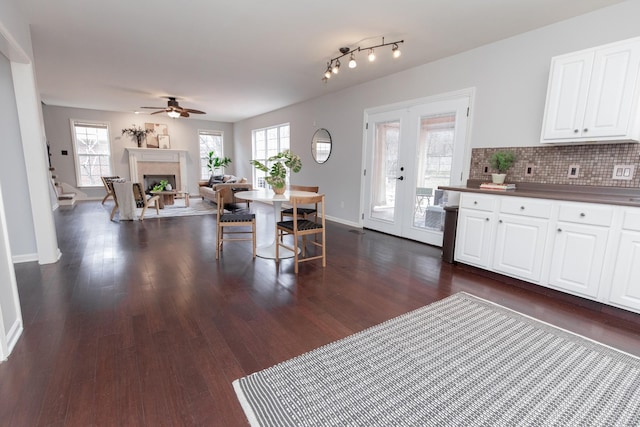 dining space featuring a fireplace, french doors, a ceiling fan, and dark wood finished floors