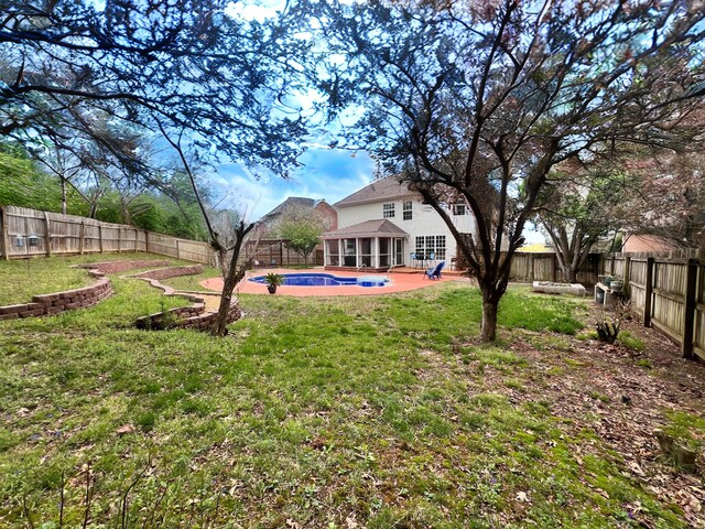 view of yard with a fenced backyard, a fenced in pool, a sunroom, and a patio