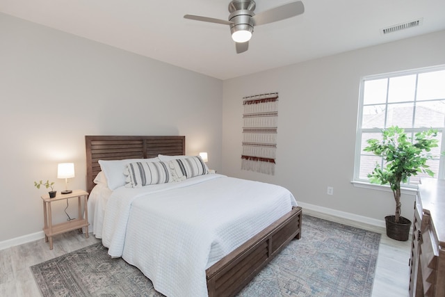 bedroom with light wood finished floors, baseboards, visible vents, and a ceiling fan
