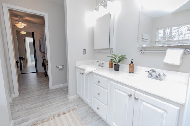 bathroom featuring double vanity, a sink, a ceiling fan, and wood finished floors