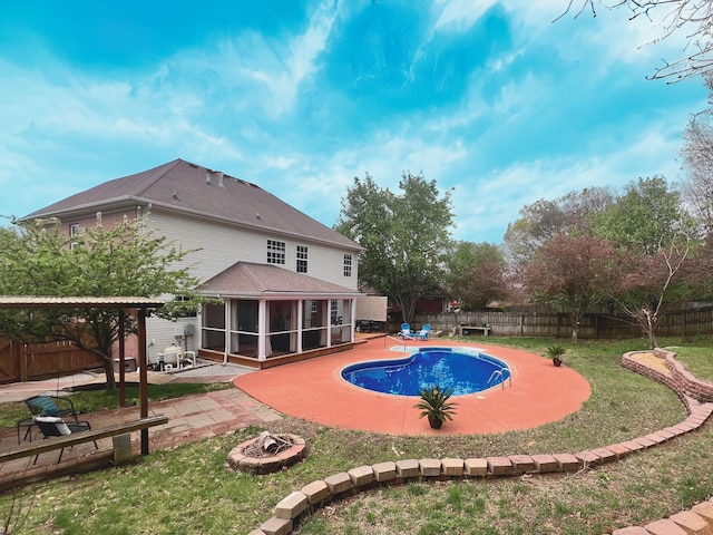 view of pool with a fenced backyard, a fire pit, a sunroom, and a patio area
