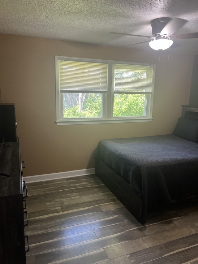 bedroom with baseboards, a textured ceiling, ceiling fan, and dark wood finished floors
