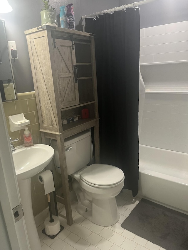 bathroom with tile patterned floors, toilet, shower / tub combo with curtain, and tile walls