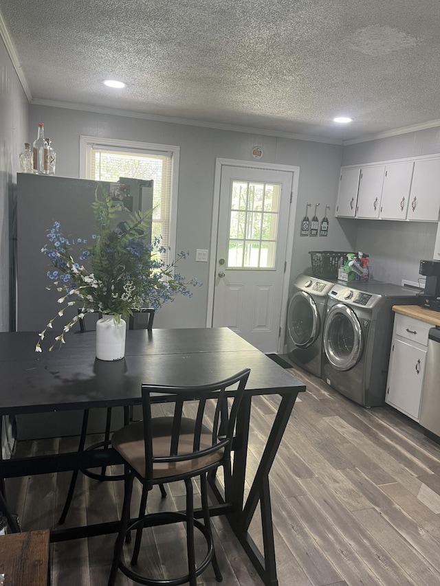 laundry area featuring ornamental molding, light wood-style floors, laundry area, a textured ceiling, and independent washer and dryer