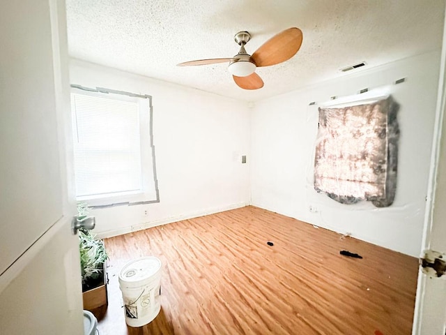 spare room featuring wood finished floors, visible vents, a textured ceiling, and ceiling fan
