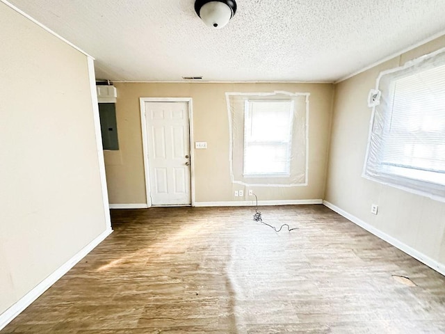 spare room featuring a wealth of natural light, wood finished floors, a textured ceiling, and baseboards