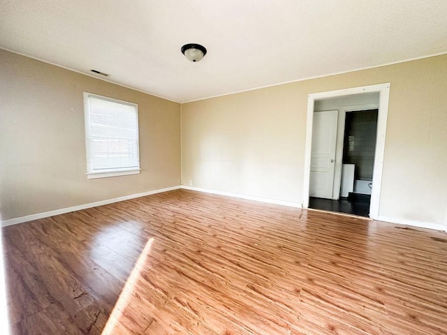 spare room with baseboards, wood finished floors, and visible vents