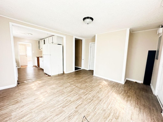 unfurnished living room featuring baseboards, wood finished floors, and a textured ceiling