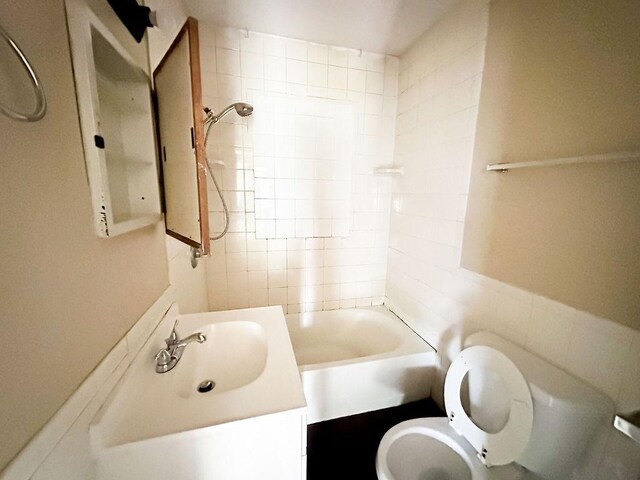 bathroom with toilet, vanity, and tile walls