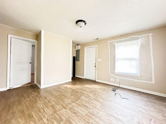 unfurnished room with baseboards, wood finished floors, and a textured ceiling