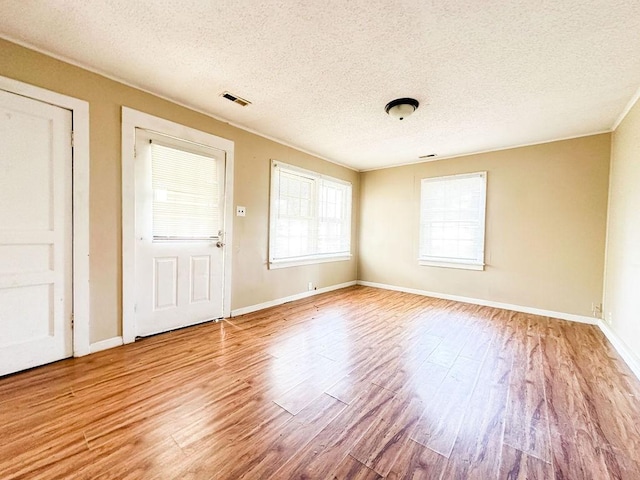 unfurnished room featuring baseboards, wood finished floors, and a textured ceiling