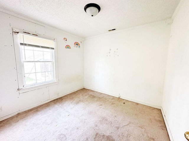 spare room with carpet floors, a textured ceiling, baseboards, and ornamental molding