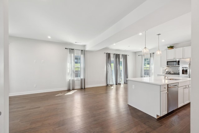 kitchen with baseboards, recessed lighting, open floor plan, appliances with stainless steel finishes, and a sink
