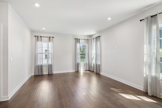 empty room featuring dark wood-type flooring, recessed lighting, baseboards, and a wealth of natural light
