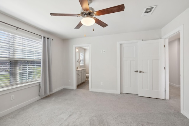 unfurnished bedroom featuring visible vents, baseboards, a ceiling fan, carpet, and connected bathroom