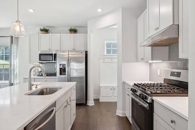 kitchen with under cabinet range hood, a sink, appliances with stainless steel finishes, and plenty of natural light