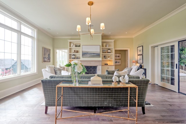 living area featuring crown molding, an inviting chandelier, baseboards, a fireplace, and wood finished floors