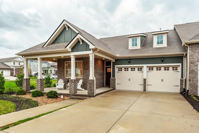 craftsman inspired home with a garage, brick siding, roof with shingles, driveway, and covered porch