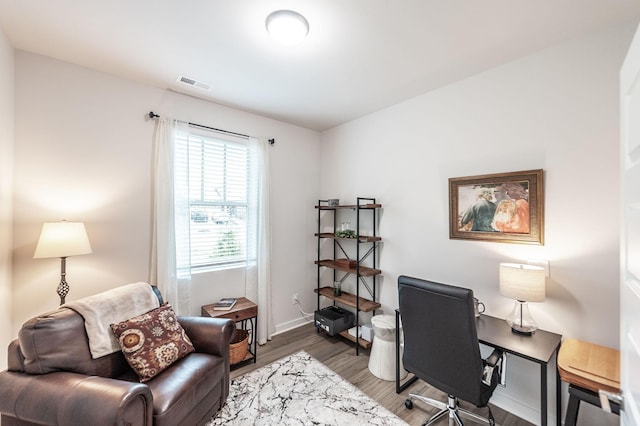 office area with light wood-type flooring, baseboards, and visible vents