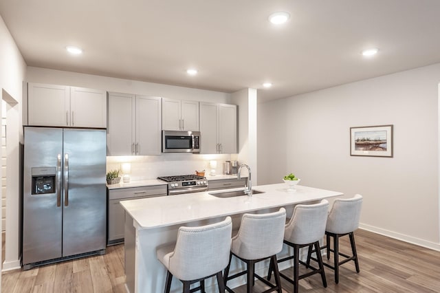 kitchen with light countertops, backsplash, a sink, light wood-style flooring, and stainless steel appliances