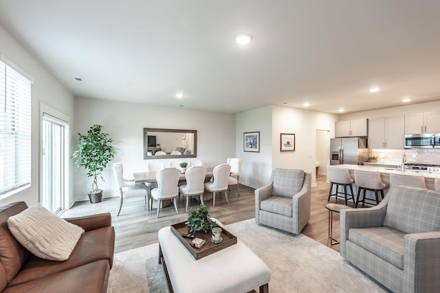 living room featuring light wood finished floors, baseboards, and recessed lighting