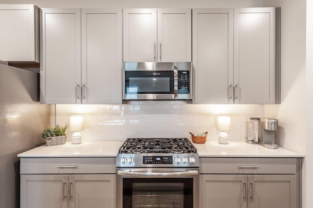 kitchen featuring light countertops, stainless steel appliances, backsplash, and gray cabinets