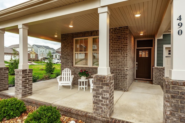 view of exterior entry with covered porch and brick siding