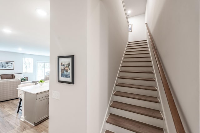stairs with wood finished floors and recessed lighting