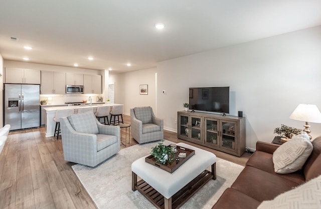 living area with baseboards, recessed lighting, and light wood-style floors