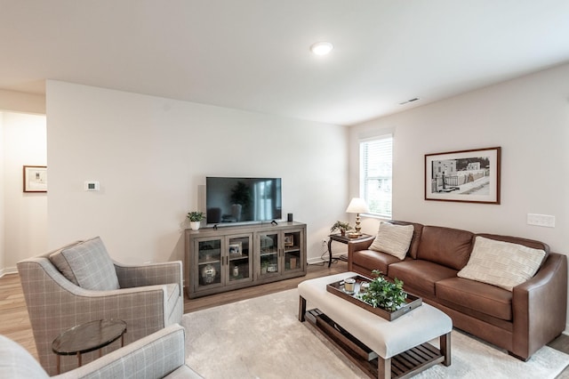 living room featuring baseboards, visible vents, and light wood-style flooring