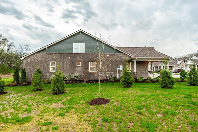 rear view of property featuring brick siding and a yard