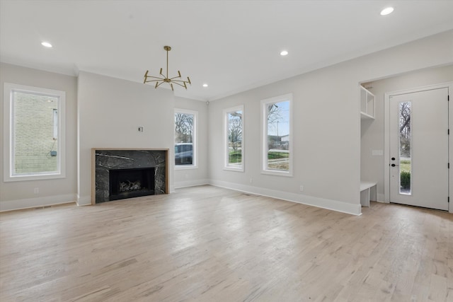unfurnished living room with a premium fireplace, baseboards, light wood finished floors, and recessed lighting