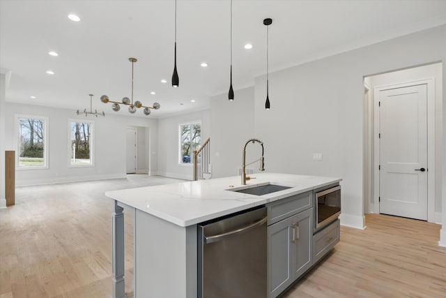 kitchen with light wood-style flooring, a kitchen island with sink, stainless steel appliances, a sink, and gray cabinetry