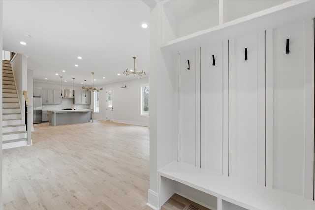 mudroom featuring baseboards, light wood-type flooring, recessed lighting, and an inviting chandelier