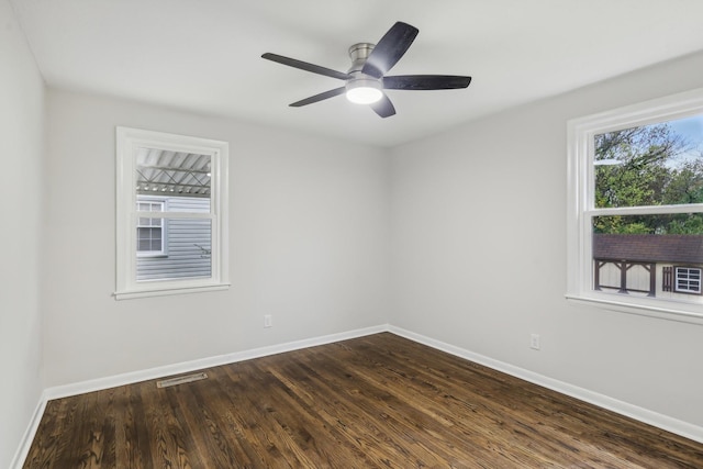 spare room featuring visible vents, baseboards, and dark wood-type flooring