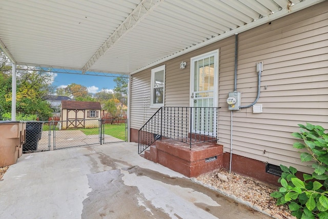 view of patio featuring an outbuilding, fence, a carport, a storage shed, and a gate