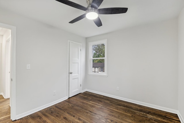 empty room featuring baseboards, a ceiling fan, and dark wood-type flooring