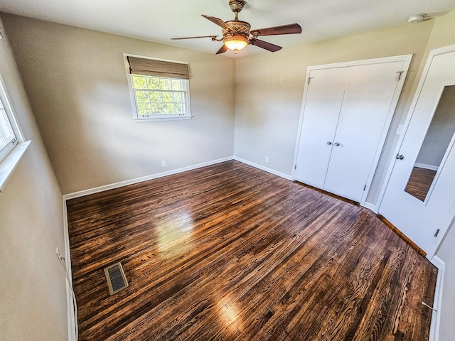 unfurnished bedroom with a closet, visible vents, baseboards, wood finished floors, and a ceiling fan